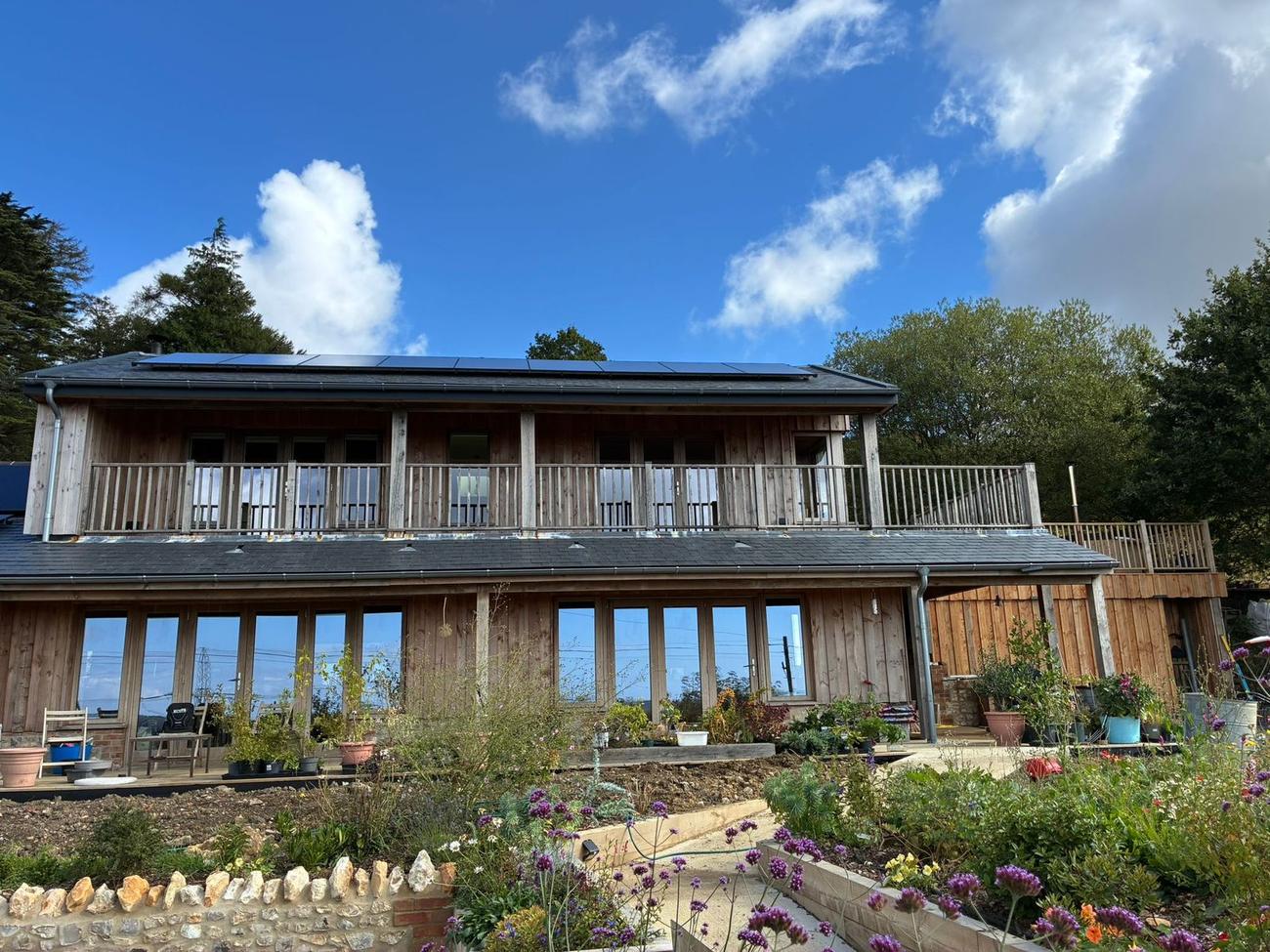 Timber-clad new build house with solar panels and balcony, West Dorset