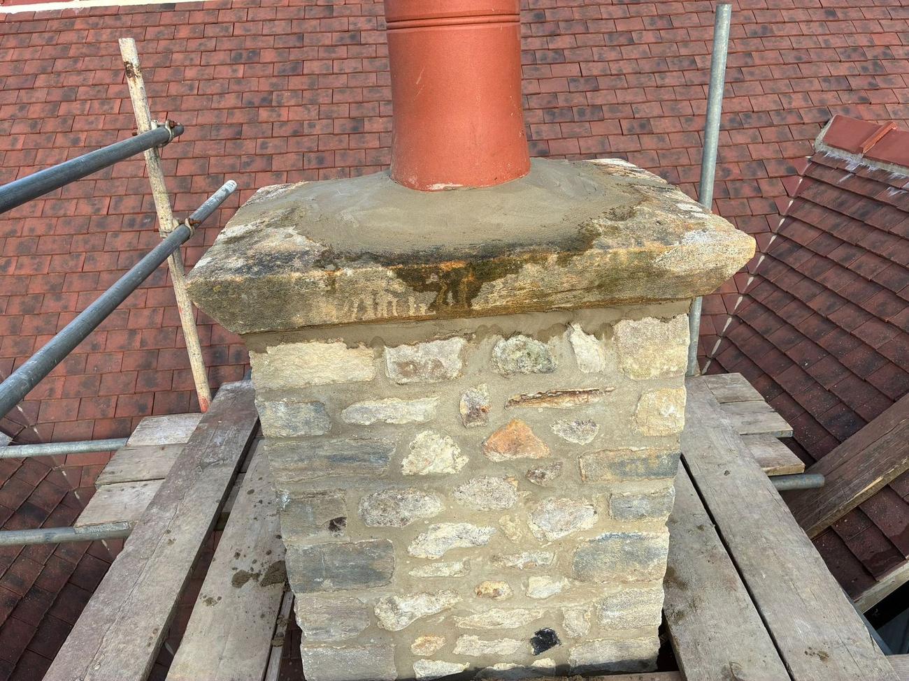 Stone chimney stack rebuilt in local rubble stone with a new pot