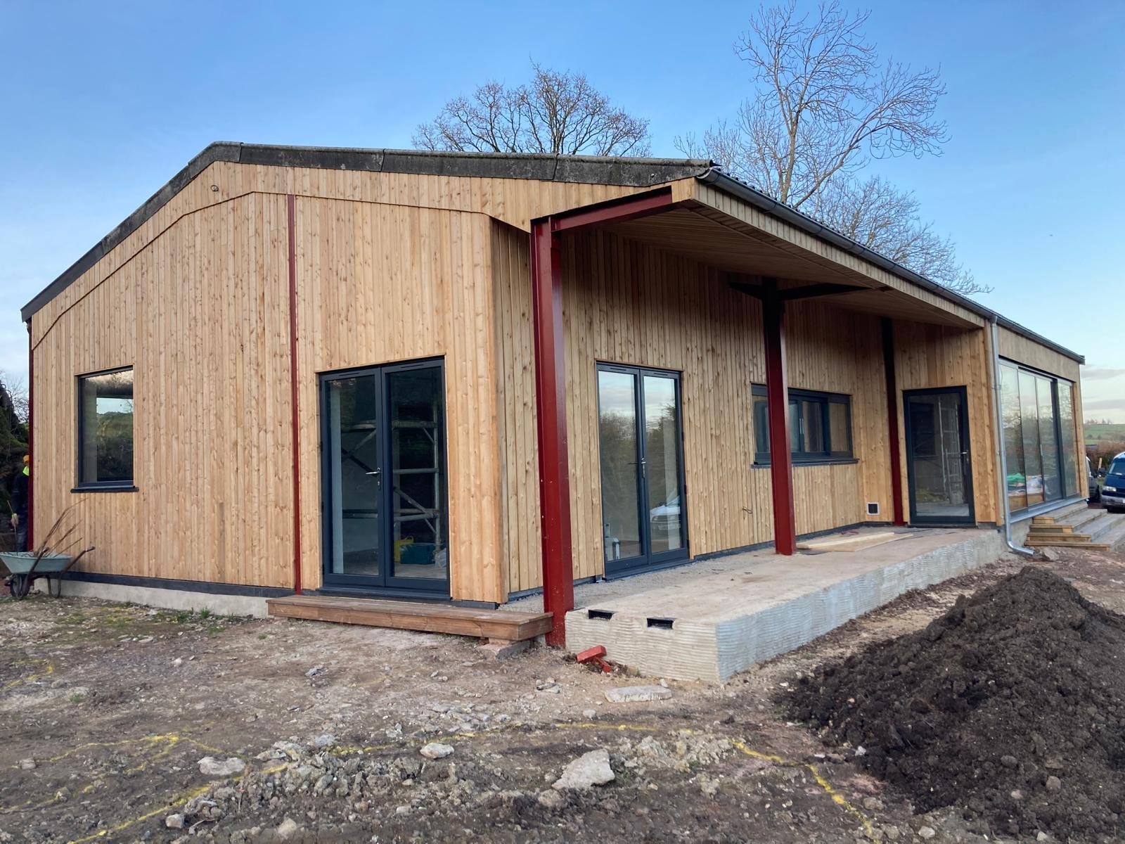 Larch-clad timber frame building with steel post, mid build